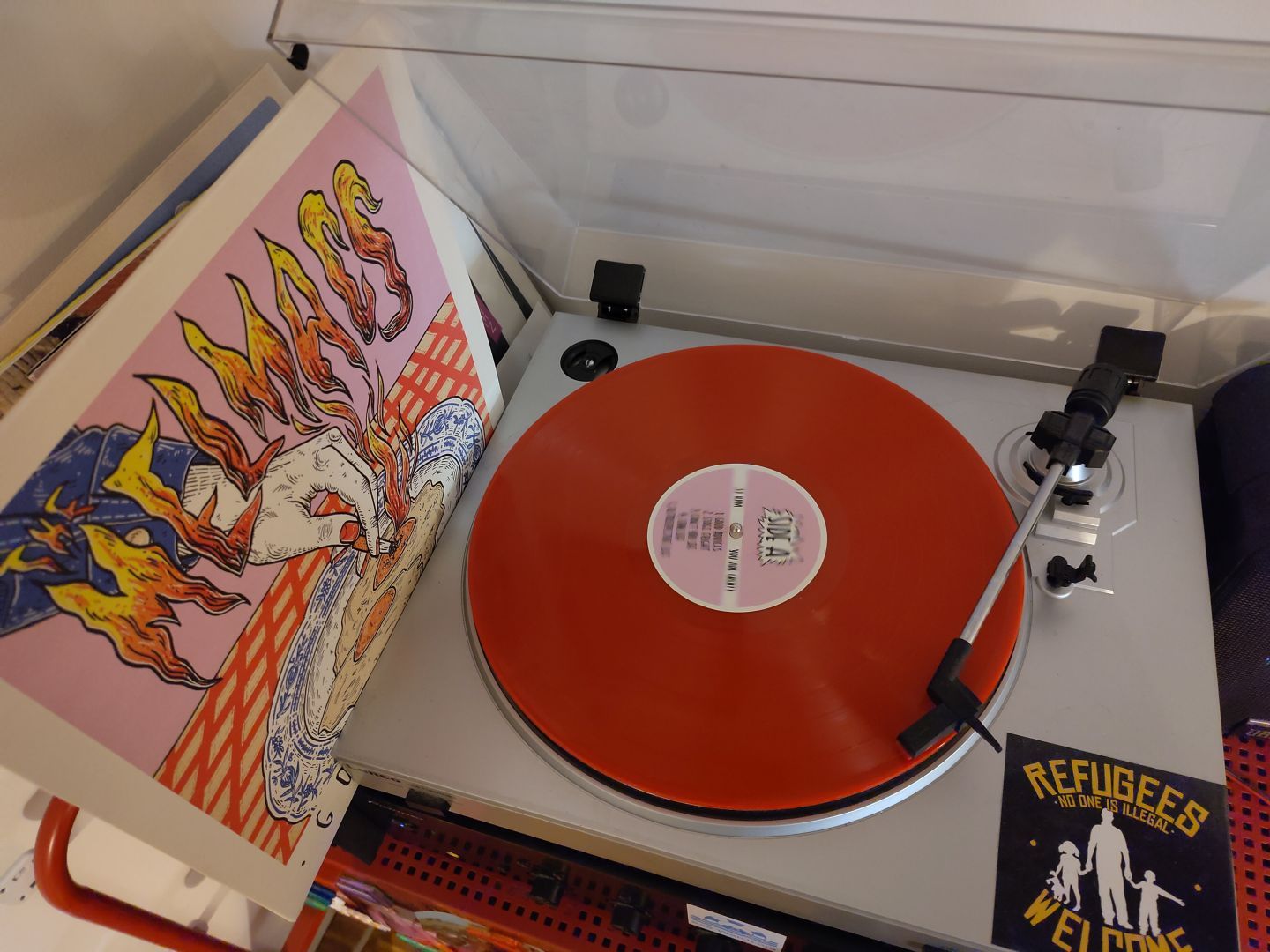 Picture of a red record, playing. On the side is the cover.